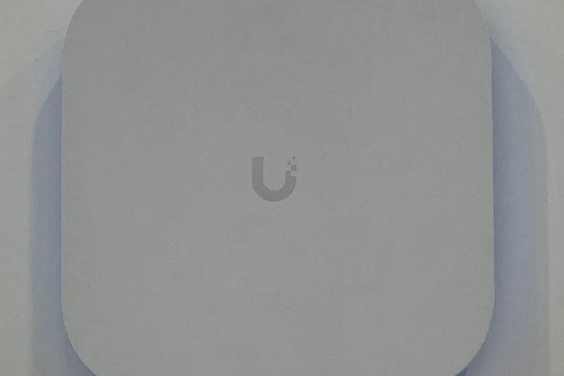 A UniFi E7 Wi-Fi 7 access point, a flat white panel